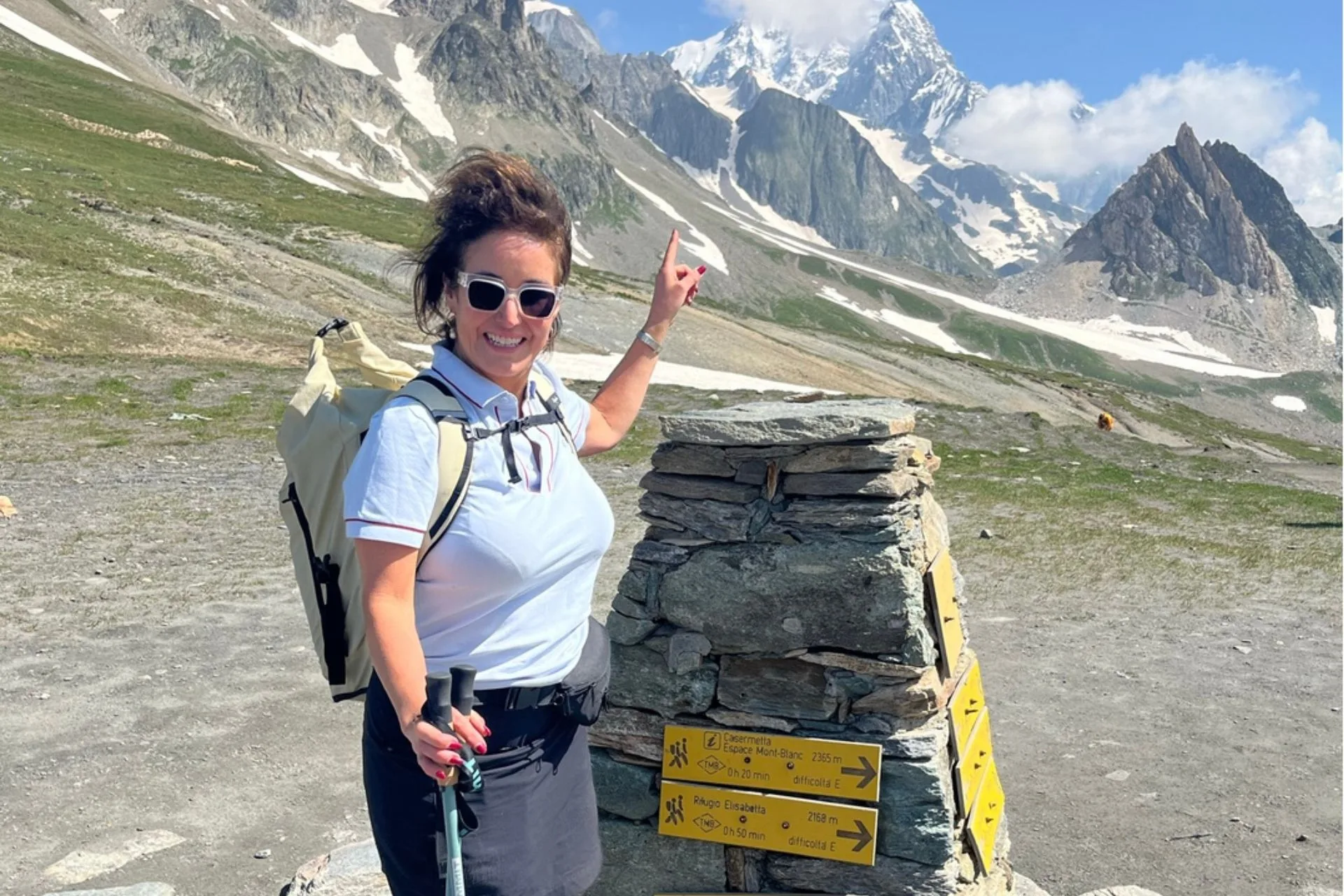 A walker celebrating at a mountain trail marker