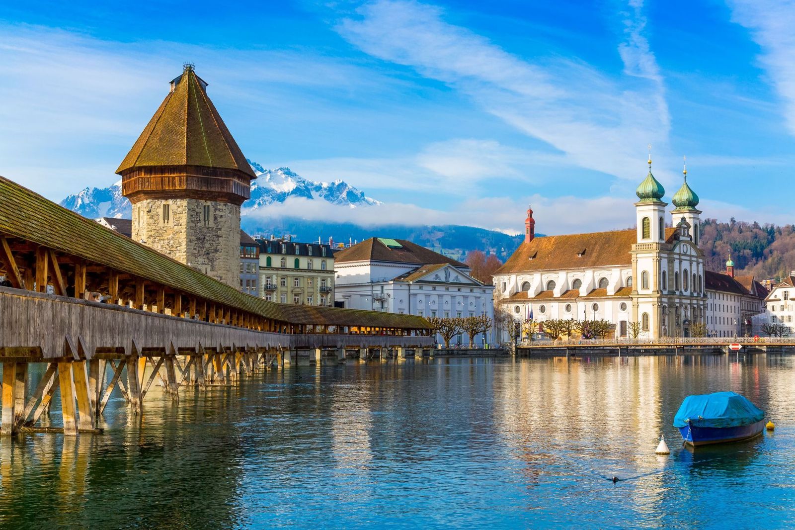 Iconic wooden Chapel Bridge (Kapellbrücke) and its octagonal Water Tower stretching across the Reuss River in Lucerne, Switzerland.