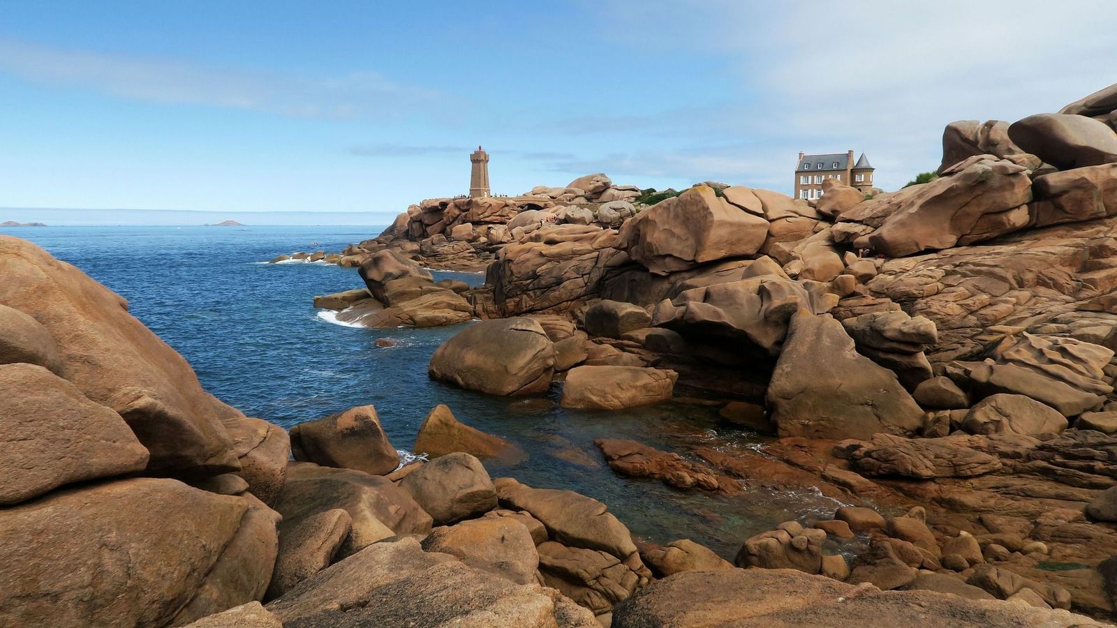 Pink granite boulders with a view of the Mean Ruz lighthouse Ploumanac'h. Brittany France