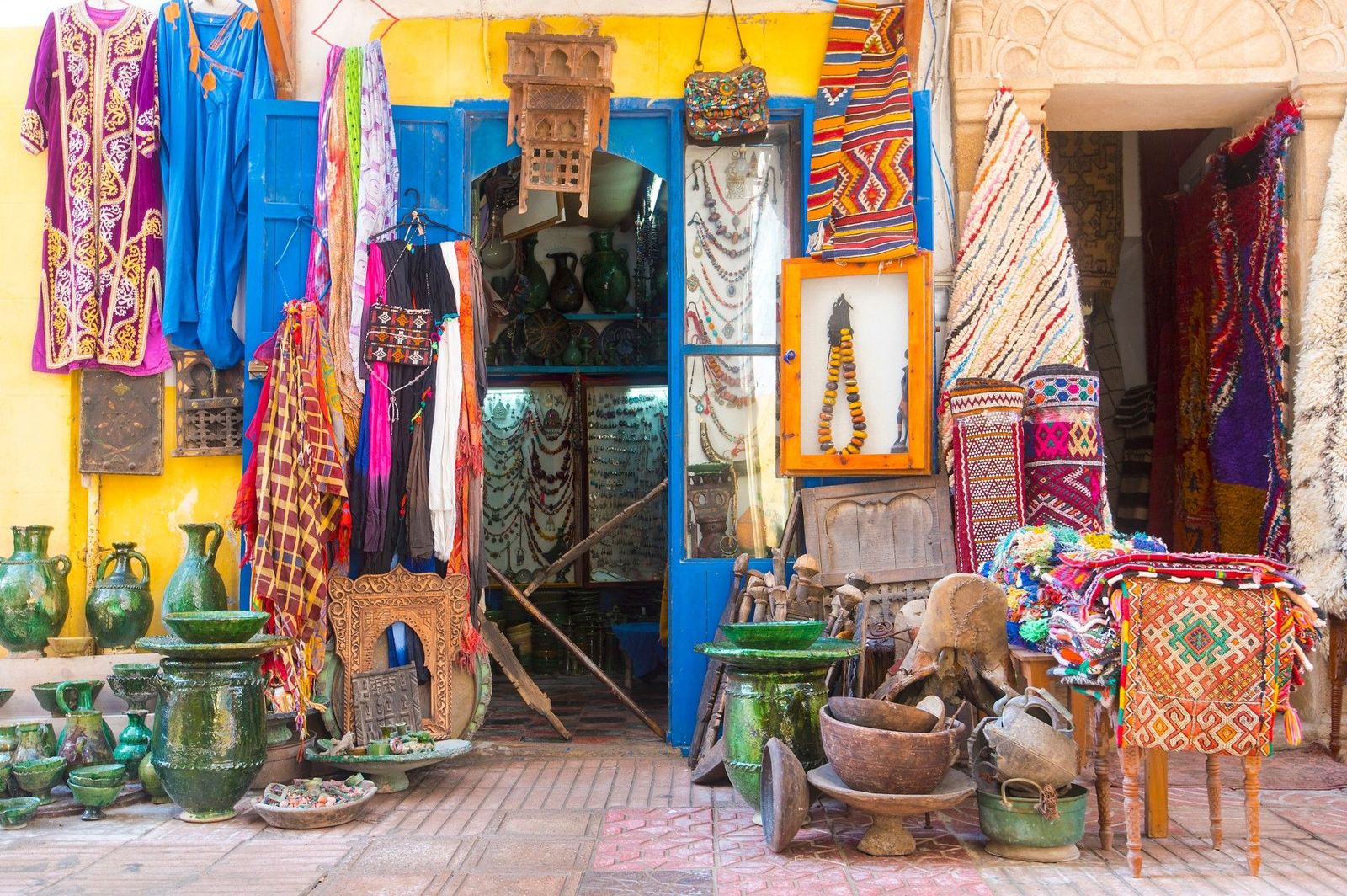 Storefront packed with traditional textiles, pottery, and jewelry in the historic Medina of Essaouira, Morocco