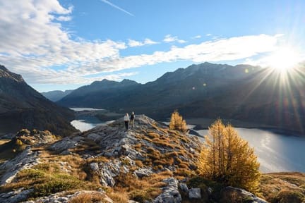 Hikers standing on a rugged, rocky ridge overlooking Lake Sils and Lake Silvaplana-supplied by Eurotrek