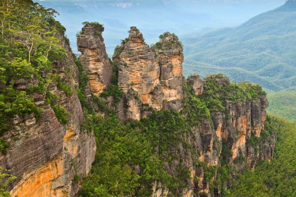 The Three Sisters sandstone rock formation rising above the forested Blue Mountains valley, New South Wales Australia walking holiday